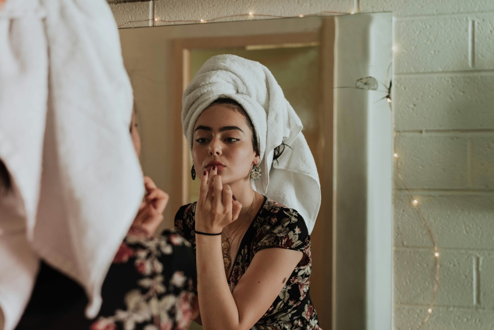 A woman applying makeup in front of a mirror