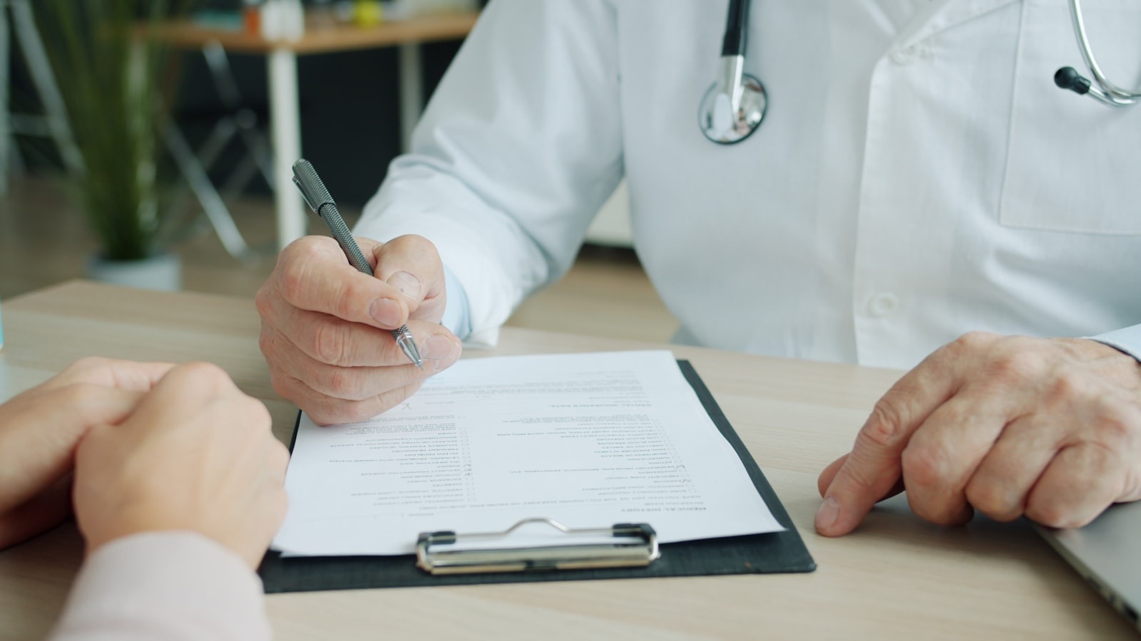 A clinician writing notes on a patient chart