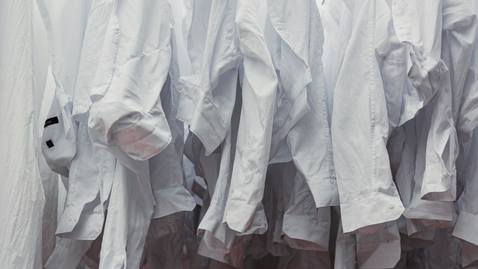 A rail of white shirts on hangers