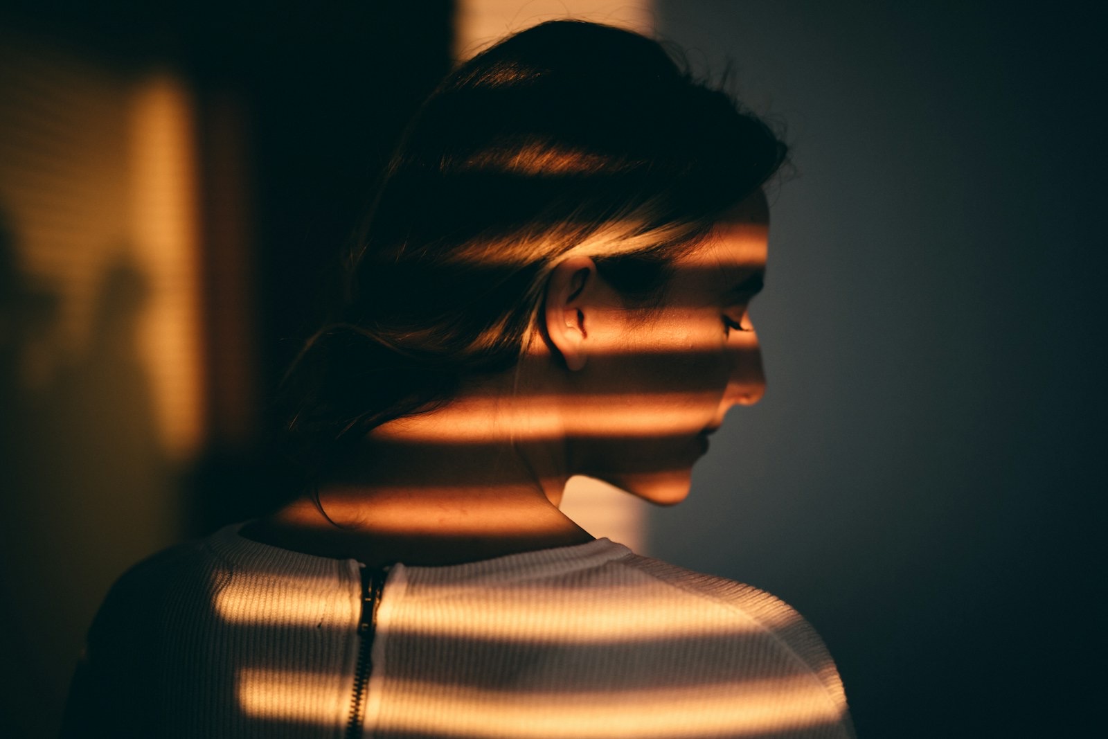 A woman standing in front of a window with sunlight coming through