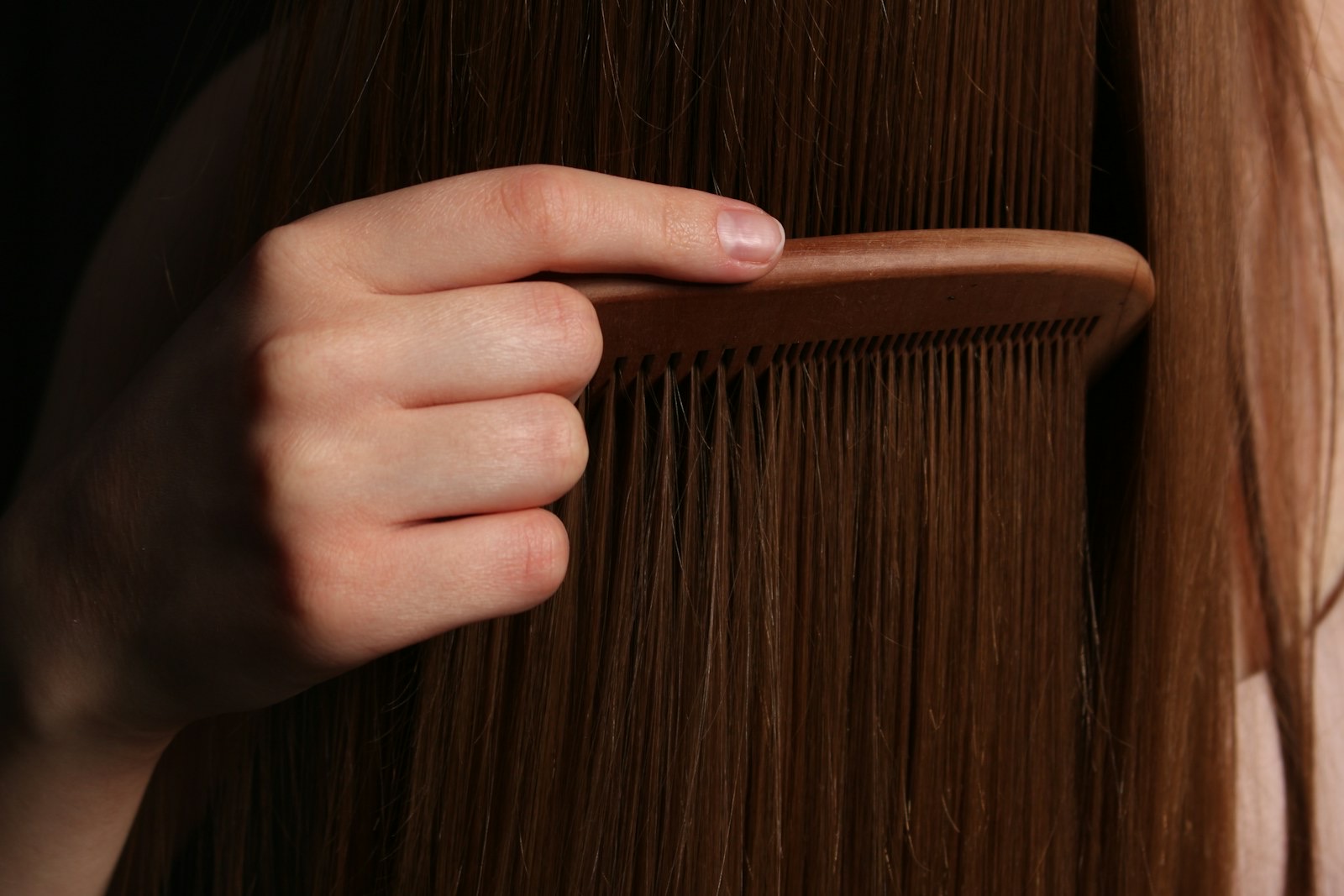 A hand combing through long brown hair