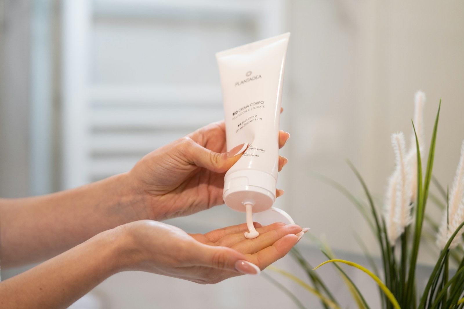 A hand holding a tube of skincare cream